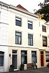 Huis met geverfde lijstgevel. Moderne winkelpui gecombineerd met die van nr 5