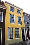 Huis met lijstgevel. Nok evenwijdig aan de straat. Voordeuromlijsting