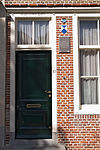 Huis met gepleisterde lijstgevel, aan de hoeken ingezwenkt. Dakkapel