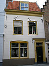 Huis met gepleisterde lijstgevel. Moderne winkelpui