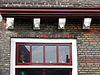 Huis met rechte gevel. Gootlijst op klosjes. Zadeldak, met nok evenwijdig aan de straat. In de zijtopgevels vlechtingen. De verdiepingen uitgekraagd op geprofileerde puibalk, rustend op consoles, versierd met gebeeldhouwde kopjes. Rode banden en rode ontlastingsbogen boven de vensters in het gele metselwerk. Vensters met kleine roedenverdeling. Kelderluik met stoeptreden