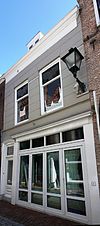 Huis met gepleisterde lijstgevel. Dakkapel. Moderne winkelpui