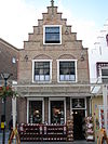 Huis met gepleisterde trapgevel. De treden afgedekt met natuurstenen platen. Puibalk