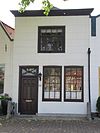 Huis met gecementeerde lijstgevel met fraaie smeedijzeren stoephekken en stoep