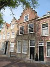 Gepleisterde lijstgevel voor huis van parterre en verdieping met schilddak. Stoep met stoeppalen