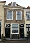 Huis met gepleisterde lijstgevel met stoeppaal