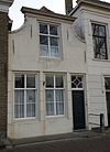 Huis met ingezwenkte lijstgevel met oorspronkelijke deur en gestoken kalf