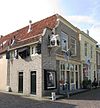 Hoekpand Nieuwstraat. Gepleisterde, ingezwenkte lijstgevel voor huis van parterre en zolderverdieping met hoog, afgewolfd zadeldak. Puntgevel aan de achterzijde