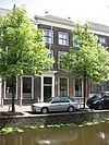 Pand onder dwars schilddak, drie vensterassen, parterre en twee verdiepingen. Eenvoudige lijstgevel met fraaie deuromlijsting en kalf, gesneden in Empirestijl. Versierde hardstenen plint. Stoeppalen met kettingen