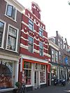 Pand met brede trapgevel, versierd met natuurstenen banden, geblokte ontlastingsbogen en geprofileerde waterlijsten. Als bekroning een opzetstuk met voluten en fronton. Tussen de vensters geblokte blinde nissen. Rechts van de gevel boven een poortje in een cartouche met jaartal