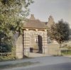 Voorzijde van het toegangspoortje van de boerderij met twee gevelstenen met hammen