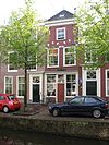 Pand, waarvan de trapgevel van zijn top is beroofd en afgedekt door een kroonlijst. Boven de vensters van de eerste verdieping geblokte ontlastingsbogen