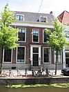 In oorsprong pand van drie vensterassen, te linkerzijde later met twee assen uitgebreid. Zadeldak tussen puntgevels. Eenvoudige deuromlijsting met pilasters, stoep met smeedijzeren hek in Lod. XIV-vormen. Hardstenen plint