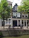Pand met gesausd trapgeveltje met onder de top een geprofileerde waterlijst. Geblokte ontlastingsbogen, natuurstenen banden en sierankers