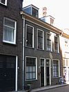 Dubbel woonhuis van vier vensterassen, parterre en verdieping. Lijstgevel met schuiframen