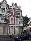 Hoekpand Reinkenstraat in neo-renaissance trant. Pand met afgeschuinde hoek en trapgevels, gedateerd op cartouches. Versiering van banden, blokken en ontlastingsbogen. Erker op de hoek op ijzeren draagconstructie