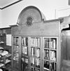 Interieur, klok boven boekenkast in werkkamer - 's-Gravenhage - 20329659 - RCE -  Huize Simpang: Interieur, klok boven boekenkast in werkkamer 