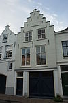 Pand met gepleisterde trapgevel met sierankers