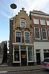 Hoekpad Visbrug. Late Dordtse trapgevel met gezakte vensters, waarin Empire schuiframen. Pand met schilddak, waarin dakvenster