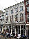 Pand achter brede gepleisterde lijstgevel ter breedte van vier vensters