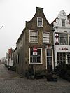 Pand met achterhuis en IJsselstenen tuitgevel met rode strekken boven de vensters en geprofileerde topafdekking. Stoep