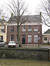 Deftig herenhuis onder hoog zadeldak, gevel met ramen uit de bouwtijd. Hoekpilasters. Stoep met rechts een stoeppaal