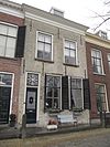 Pand opgetrokken uit secundair verwerkte Gobertangerblokken onder een rechte lijst. Empireramen, stoeppalen