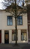 Huis met gepleisterde lijstgevel. Dakvenster met vleugelstukken, in het schilddak