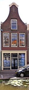 Pand met klokgevel met zijvoluten en geprofileerd, segmentvormig topfronton, waarin schelpmotief (Lod.XIV). Pui; Empire ramen