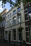 Twee huizen achter een gepleisterde lijstgevel met Lod.XIV-consoles onder de kroonlijst en stucversieringen. Inwendig een Lod.XV-plafond