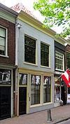 Pand met gepleisterde lijstgevel voor huis met schilddak. Empire schuiframen in de verdieping
