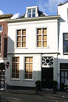 Pand met gepleisterde lijstgevel met enigszins gewijzigde pui, waarin deuromlijsting met gecanneleerde pilasters en bovenlicht