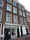 Pand, bestaande uit twee eenvoudige bakstenen gevels met rechte kroonlijst. Boven de oude roedenverdeling vensters. Onderpui in 19e eeuw aangebracht