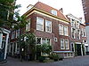 Pand met verdieping en schilddak, dat achter aansluit tegen een tuitgevel met rookkanaal. De gevels worden afgesloten door houten kroonlijsten. Aan de zijde van de Pieterskerkstraat een karakteristieke winkelpui
