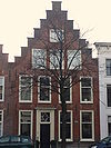 Pand met trapgevel met geblokte bogen boven de vensters. Hardstenen stoep met palenveranderd