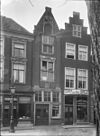 Pand met smalle puntgevel met beeldhouwwerk en oorspronkelijke kruisvensters. Aan weerszijden pilasters