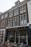 Fragment van gevel. Kruiskozijnen waarboven strekken met maskersluitsteen, rechte kroonlijst, onderpui modern