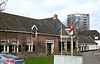Boerderij, bestaande uit woonhuis met driezijdig uitgebouwde voorkamer, schilddak en vensters met blinden en negenruitsschuiframen, alsmede uit een langgerekte stal onder pannen zadeldak. Bij het woonhuis een deur met panelen in omlijsting van pilasters met hoofdgestel. Zesruitsbovenlicht