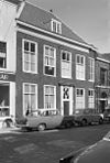 Pand met bakstenen gevel met rechte kroonlijst, deuromlijsting en bovenlicht. Hardstenen stoep met palen