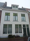 Pand met gepleisterde gevel met rechte kroonlijst. Mansardedak van latere tijd