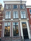 Pand met bakstenen gevel met op verdieping teruggewerkte traveeën, afgedekt met rechte kroonlijst. Deuromlijsting. Hardstenen stoep met gesmeed ijzeren hek