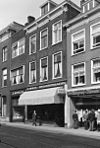 Pand met bakstenen gevel met rechts kroonlijst consoles met leeuwenmaskers, moderne winkelpui