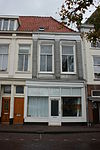 Twee panden met verminkte bakstenen gevels met rechte kroonlijst. De verdieping voorzien van Dorische pilasterstellingen en fries van metselmozaïek