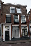 Pand met bakstenen lijstgevel. Deur met omlijsting. Bovengevel vernieuwd