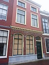 Pand met gepleisterde gevel met rechte kroonlijst. Zadeldak
