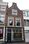 Pand met tuitgevel met sierankers, bovengevel hersteld 1945