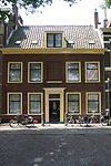 Pand met brede gevel met rechte kroonlijst. Zadeldak over lengte der gevel. Gesneden Louis Seize deuromlijsting