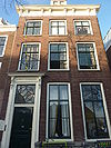 Pand met lijstgevel met houten deuromlijsting. Hardstenen stoep met stoeppalen