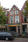 Pand met geverfde trapgevel met strekken en maskersluitingen boven de vensters. Onderpui verbouwd