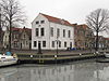 Hoekpand, gepleisterd en met gewijzigde puntgevel. Onderpui in de trant van ca. 1800 met negenruitsramen